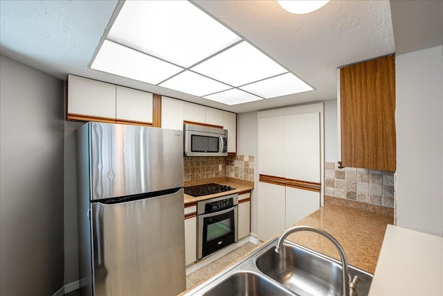 kitchen with tasteful backsplash, sink, stainless steel appliances, and white cabinets