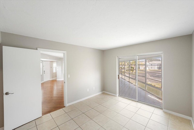 empty room featuring a textured ceiling and light tile patterned floors