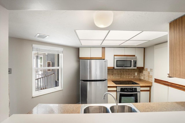 kitchen with stainless steel appliances, tasteful backsplash, sink, and white cabinets