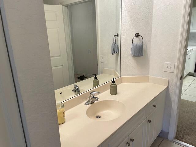 bathroom with tile patterned flooring, a textured wall, and vanity