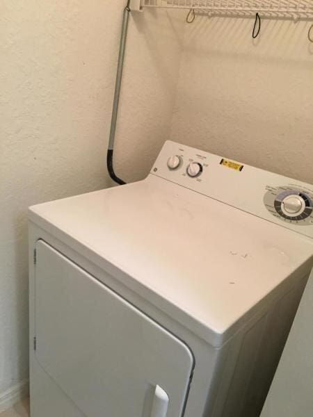 washroom featuring washer / dryer, laundry area, and a textured wall