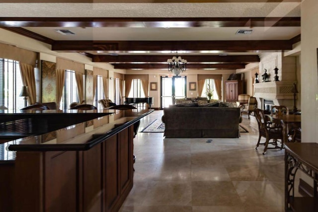 living room featuring a notable chandelier, visible vents, beamed ceiling, and a glass covered fireplace