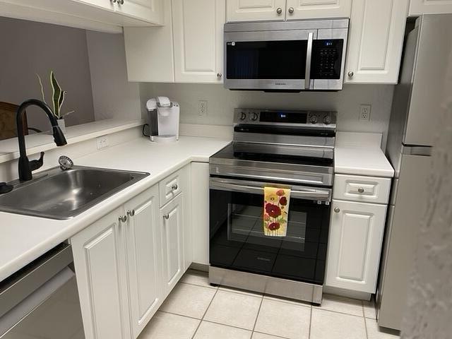 kitchen featuring white cabinetry, stainless steel appliances, a sink, and light countertops