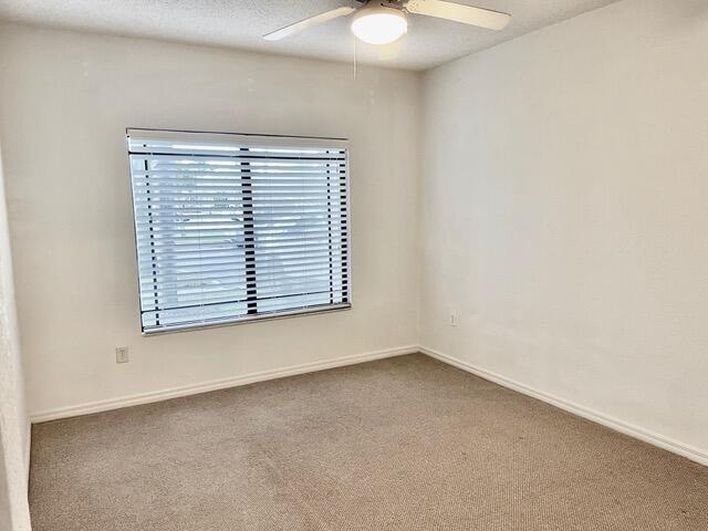 unfurnished room with carpet floors, a textured ceiling, baseboards, and a ceiling fan