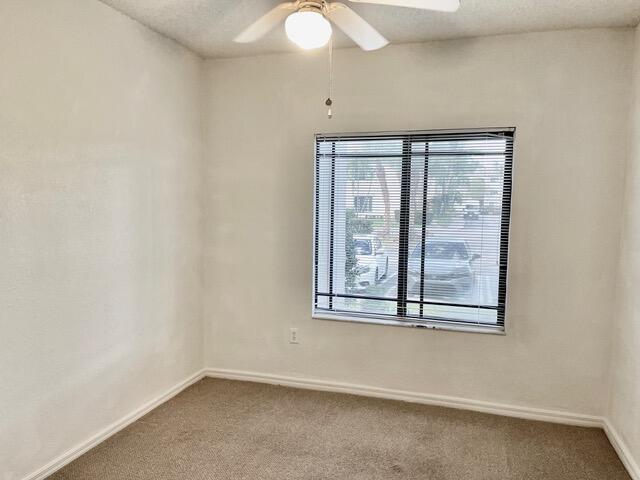 spare room featuring carpet floors, ceiling fan, baseboards, and a textured ceiling