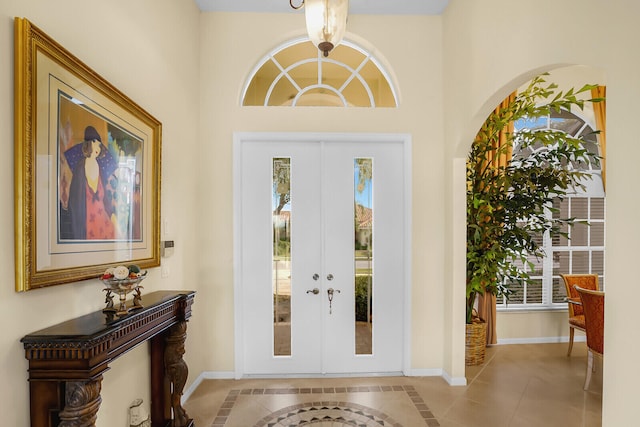 foyer entrance with light tile patterned flooring, a healthy amount of sunlight, and french doors