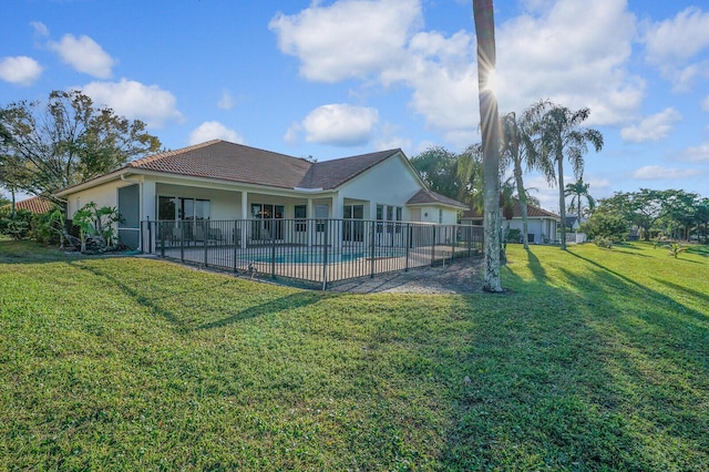 rear view of property with a fenced in pool, a yard, and a patio area