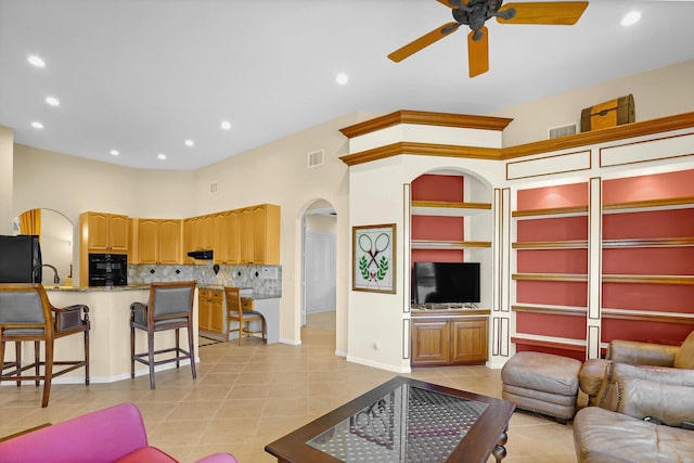 living room with light tile patterned flooring, ceiling fan, and a towering ceiling