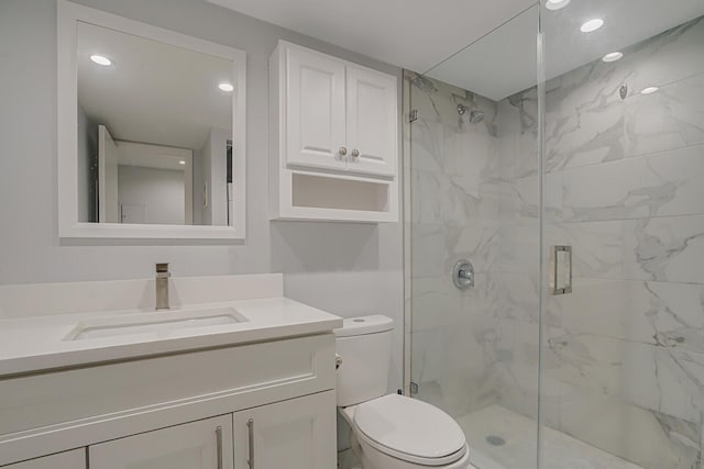 bathroom with a shower with door, vanity, and toilet