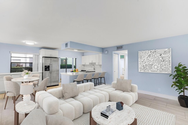 living room with sink, light hardwood / wood-style flooring, and a healthy amount of sunlight