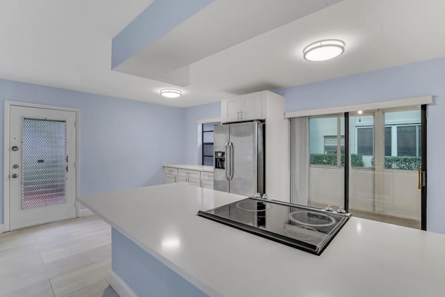 kitchen with white cabinets, stainless steel fridge, and black electric cooktop