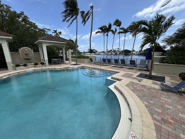 view of swimming pool featuring a gazebo, a water view, and a patio