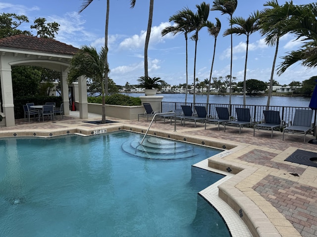 view of swimming pool with a patio and a water view