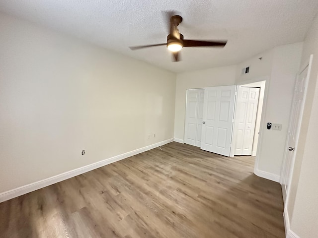 unfurnished bedroom featuring hardwood / wood-style flooring, a textured ceiling, ceiling fan, and a closet