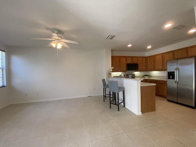 kitchen featuring light tile patterned flooring, a breakfast bar, stainless steel fridge with ice dispenser, ceiling fan, and kitchen peninsula