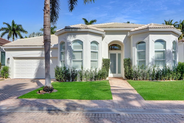 mediterranean / spanish-style home featuring a garage and a front lawn