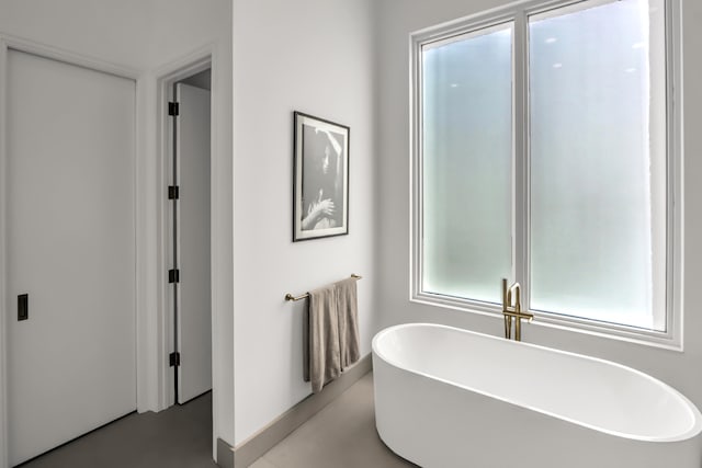 bathroom featuring a tub to relax in and concrete floors