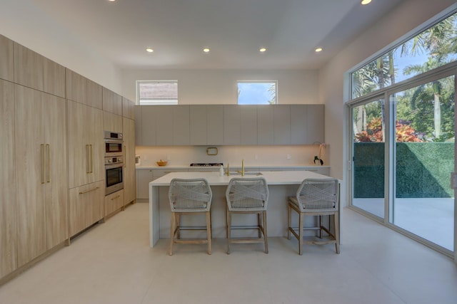 kitchen with plenty of natural light, a breakfast bar, and a center island with sink