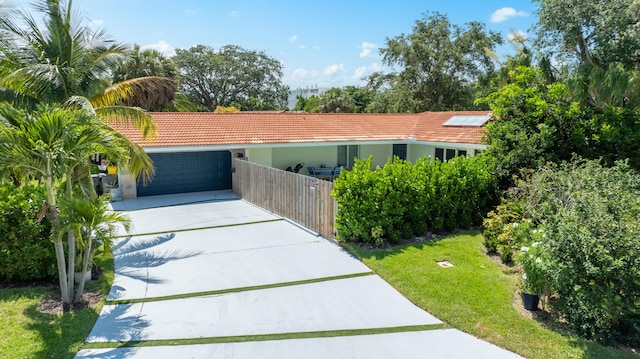 view of front of house featuring fence, a front yard, a tile roof, and stucco siding