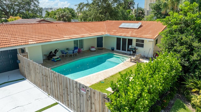 rear view of property with a fenced in pool, a tile roof, stucco siding, a patio area, and a fenced backyard