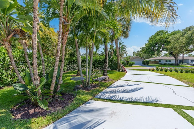 view of home's community with concrete driveway and a yard