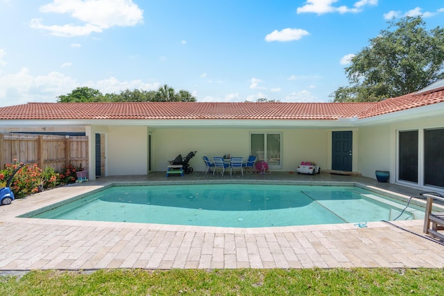 rear view of property with a tile roof, fence, a fenced in pool, and stucco siding