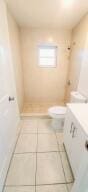 bathroom with vanity, tile patterned floors, toilet, and a shower