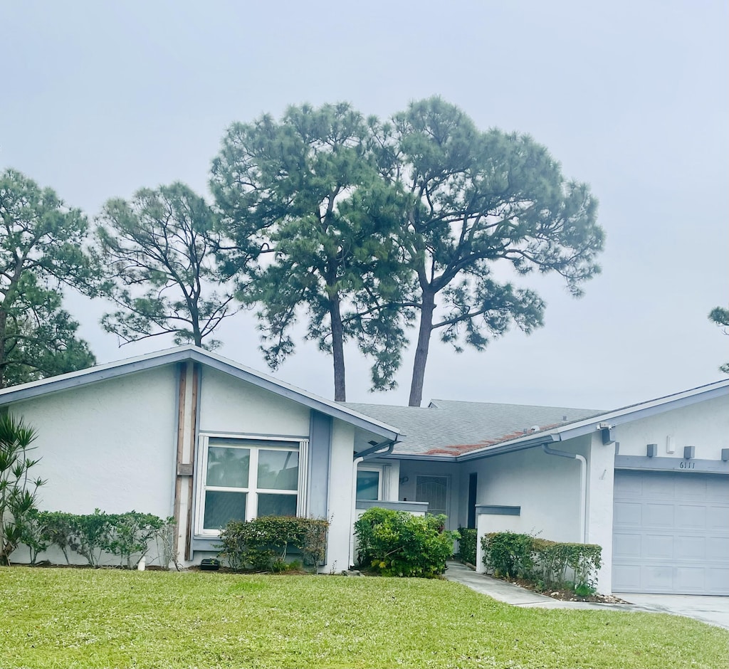 ranch-style home with a garage and a front lawn