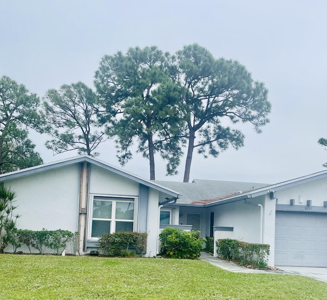 ranch-style home with an attached garage, a front lawn, concrete driveway, and stucco siding