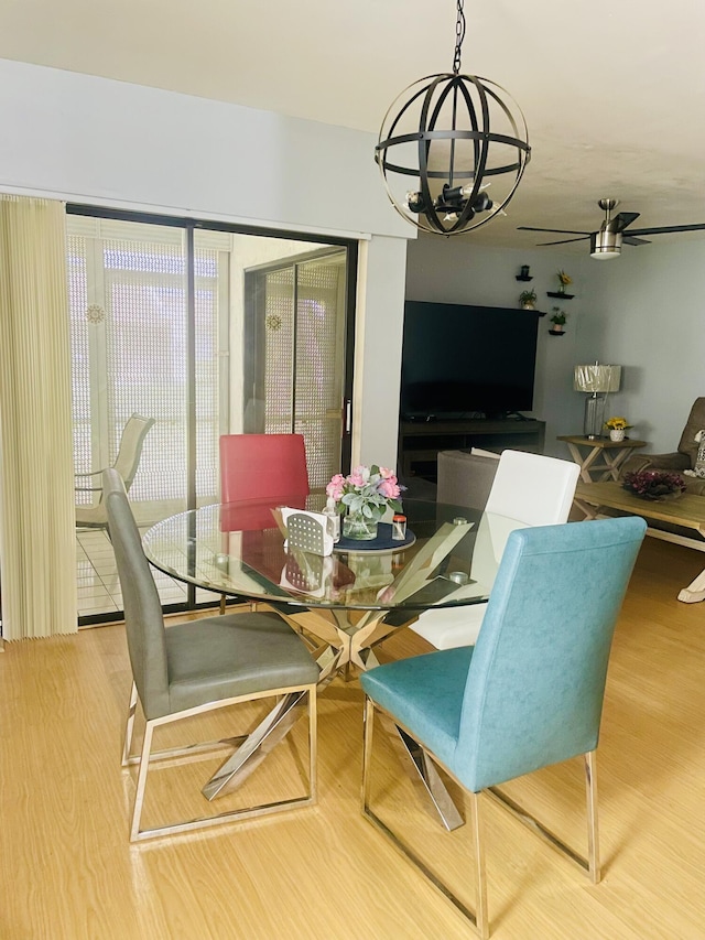 dining room featuring ceiling fan with notable chandelier and wood finished floors