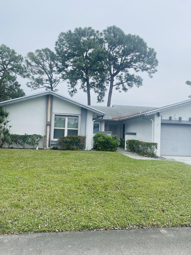 view of front facade featuring concrete driveway, a front lawn, an attached garage, and stucco siding