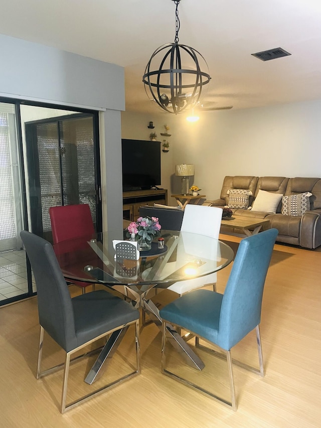 dining space with visible vents, a notable chandelier, and wood finished floors