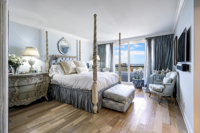 bedroom with hardwood / wood-style flooring, a wall of windows, and ornamental molding