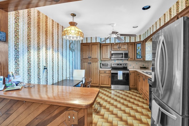 kitchen featuring decorative backsplash, hanging light fixtures, ceiling fan, kitchen peninsula, and stainless steel appliances