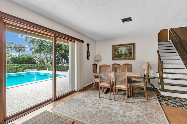 dining area with wood-type flooring and a textured ceiling