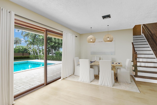 unfurnished dining area featuring wood-type flooring and a textured ceiling