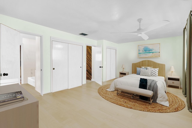 bedroom with ceiling fan, light hardwood / wood-style floors, and two closets