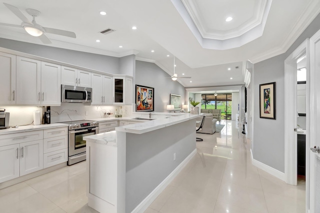 kitchen featuring appliances with stainless steel finishes, white cabinetry, a kitchen bar, light stone counters, and crown molding