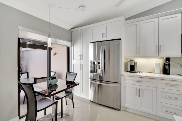 kitchen featuring white cabinets, stainless steel fridge, hanging light fixtures, light tile patterned floors, and light stone counters