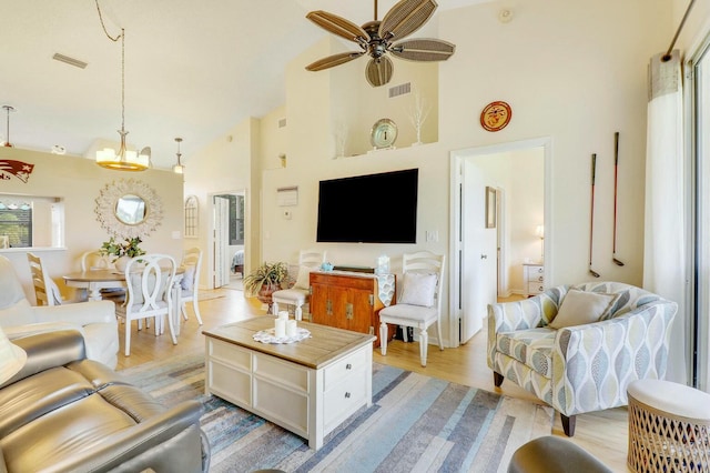 living area featuring high vaulted ceiling, light wood-type flooring, visible vents, and a ceiling fan