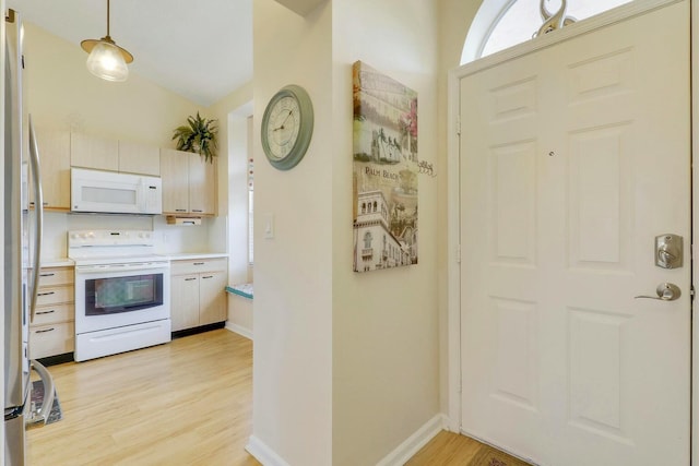 kitchen with hanging light fixtures, white appliances, and light hardwood / wood-style flooring