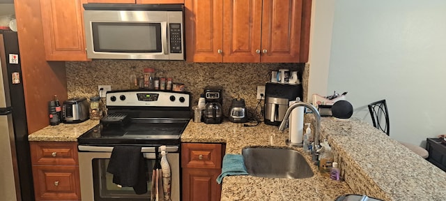 kitchen with stainless steel appliances, light stone countertops, sink, and decorative backsplash