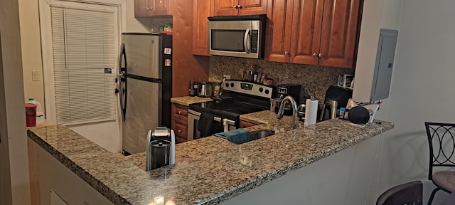 kitchen with decorative backsplash, stainless steel appliances, kitchen peninsula, and stone countertops