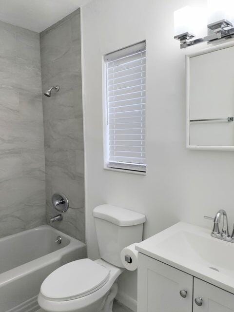 full bathroom with tiled shower / bath, vanity, and toilet