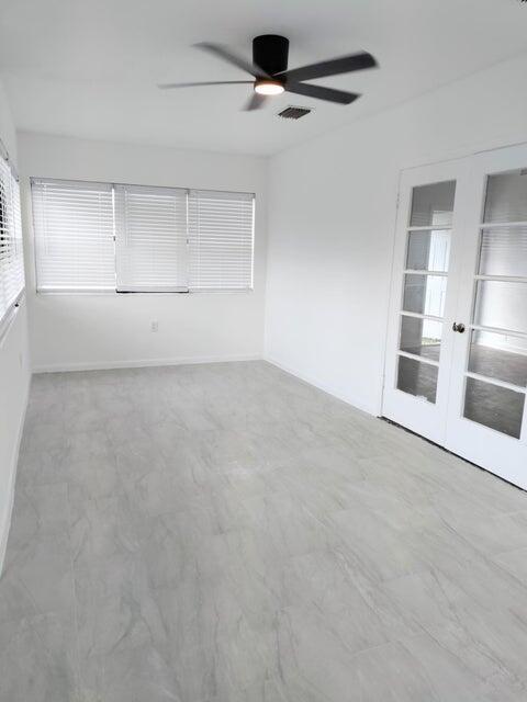 spare room featuring ceiling fan and french doors