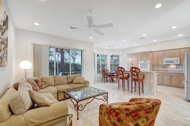 living room with light tile patterned floors and ceiling fan with notable chandelier