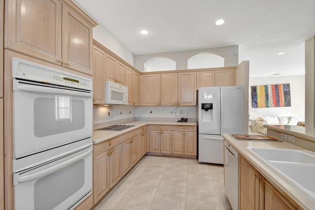 kitchen with light brown cabinetry, sink, white appliances, and backsplash