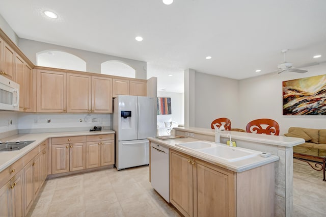 kitchen with light brown cabinetry, sink, white appliances, an island with sink, and ceiling fan