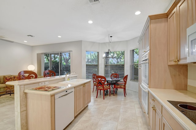 kitchen featuring light brown cabinetry, sink, hanging light fixtures, plenty of natural light, and white appliances