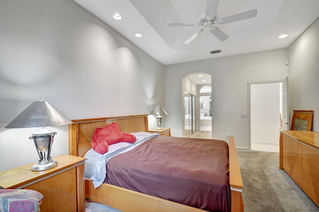 bedroom with ceiling fan, light colored carpet, and ensuite bathroom